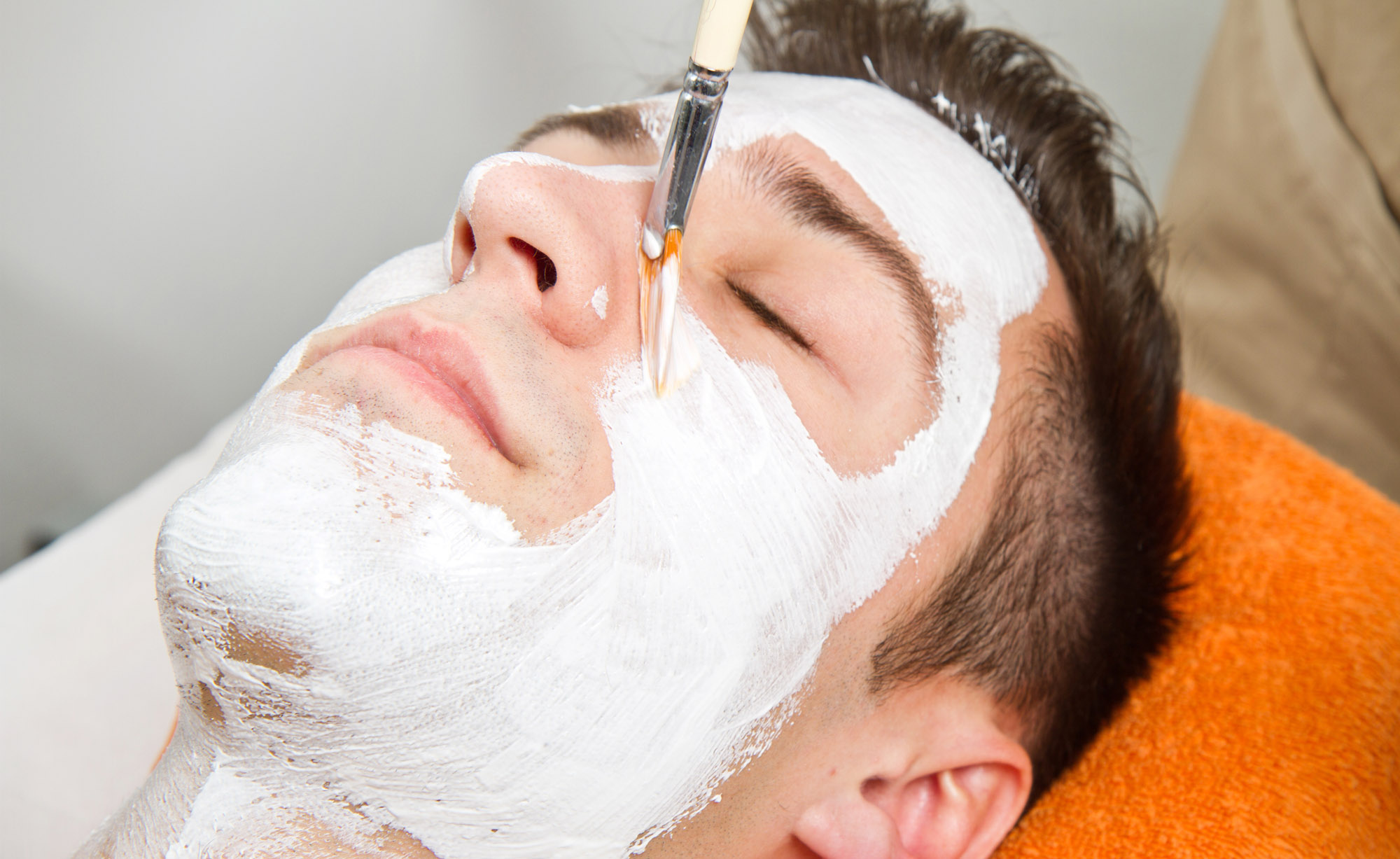 Therapist Applying A Face Mask To A Beautiful Young Man In A Spa
